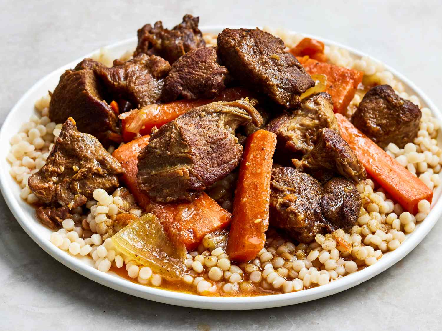 High angle looking at a plate of lamb tagine, served over couscous.