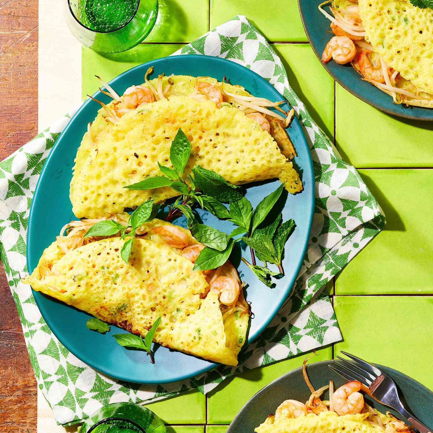 Turmeric-flavored crepes filled with shrimp and mung bean sprouts on a turquoise plate