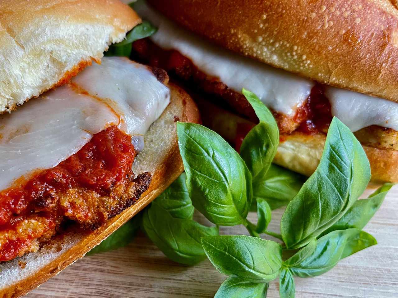 A chicken Parm cutlet on a roll garnished with basil