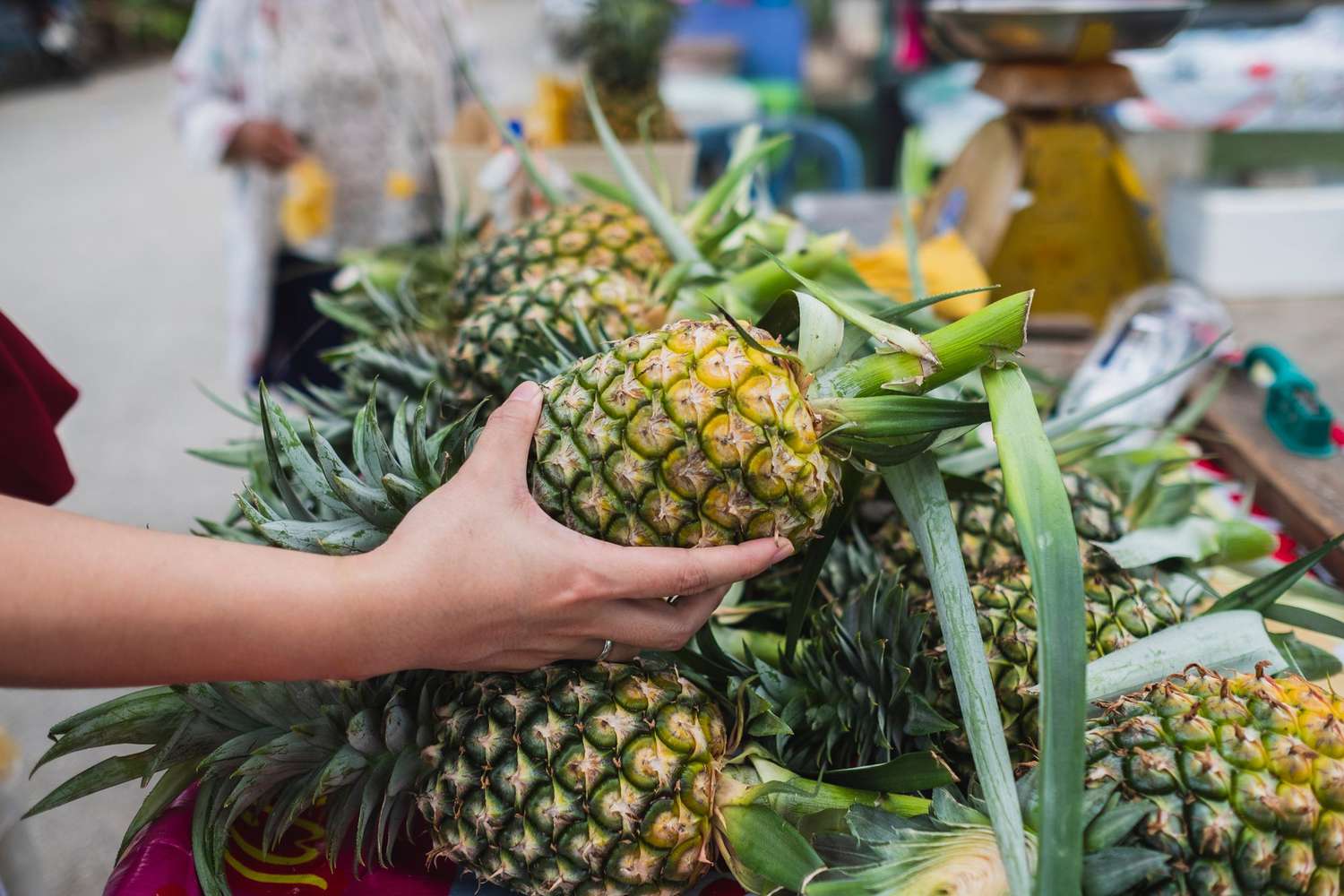 Close-Up Of Woman Buying Pineapple At Market Stall