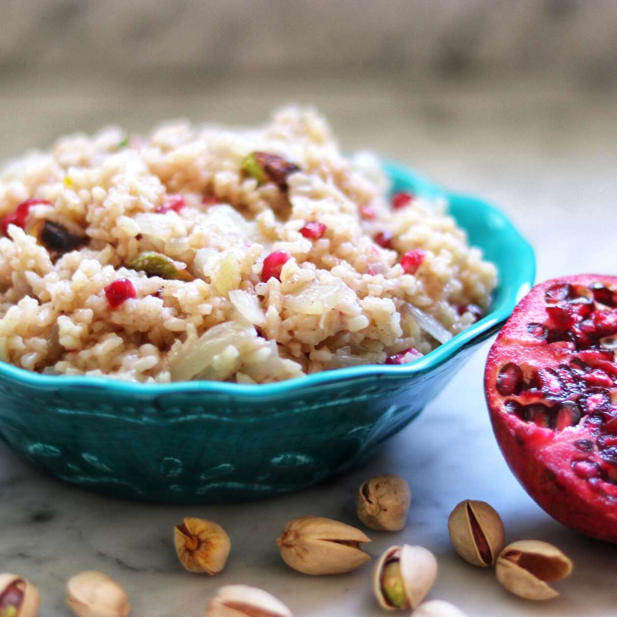 Middle Eastern Rice Pilaf with Pomegranate in a turquoise bowl with a pomegranate