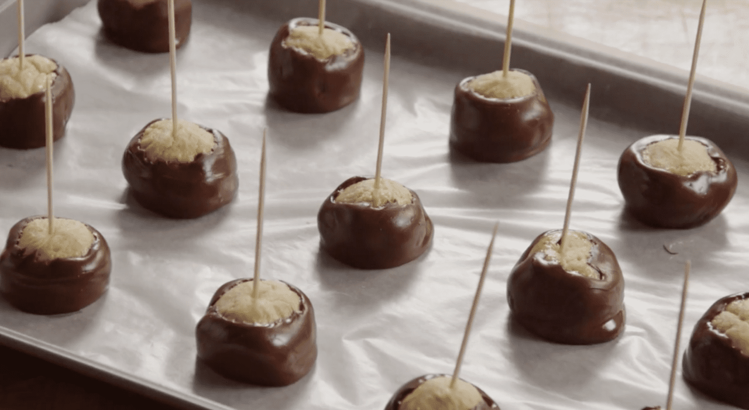 Buckeyes with toothpicks on wax-lined baking sheet