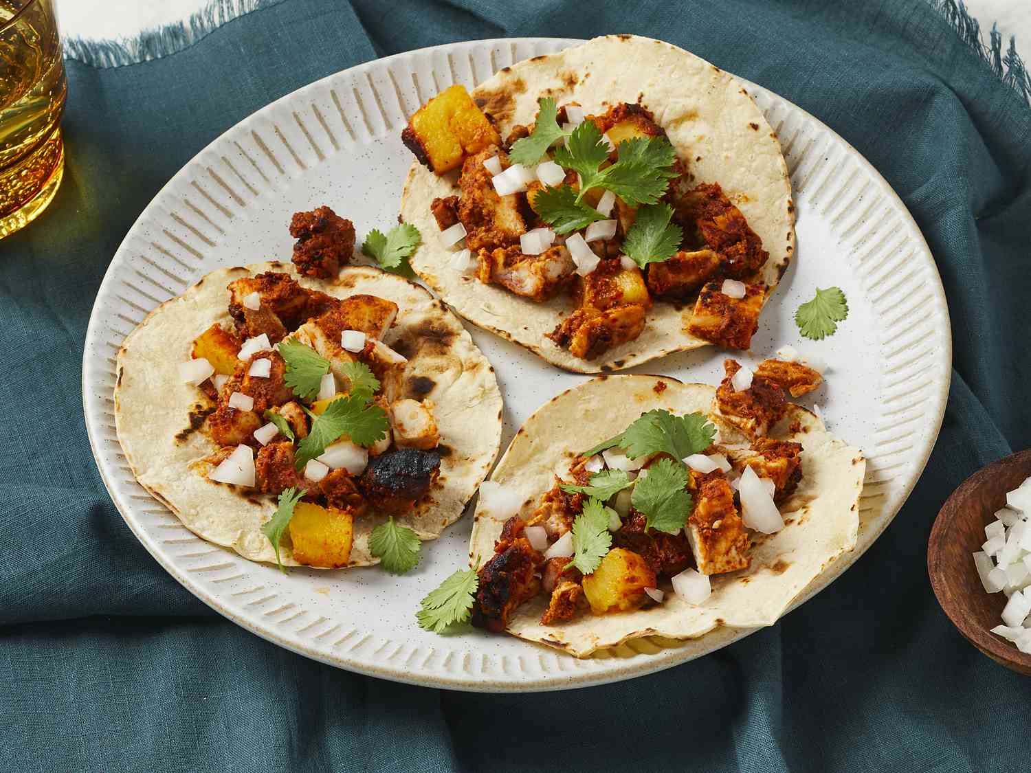 Close up on three tortillas topped with chicken al pastor