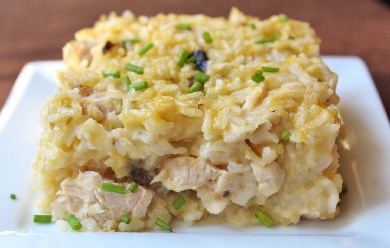 Closeup of a square serving of casserole topped with chopped chives