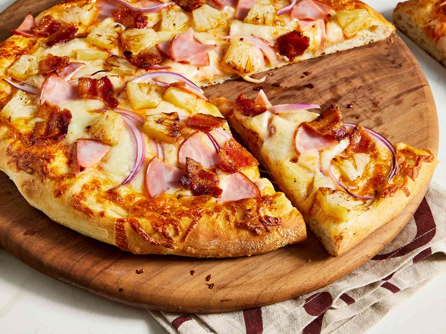 Close up on a Hawaiian pizza on a tray with a few slices missing
