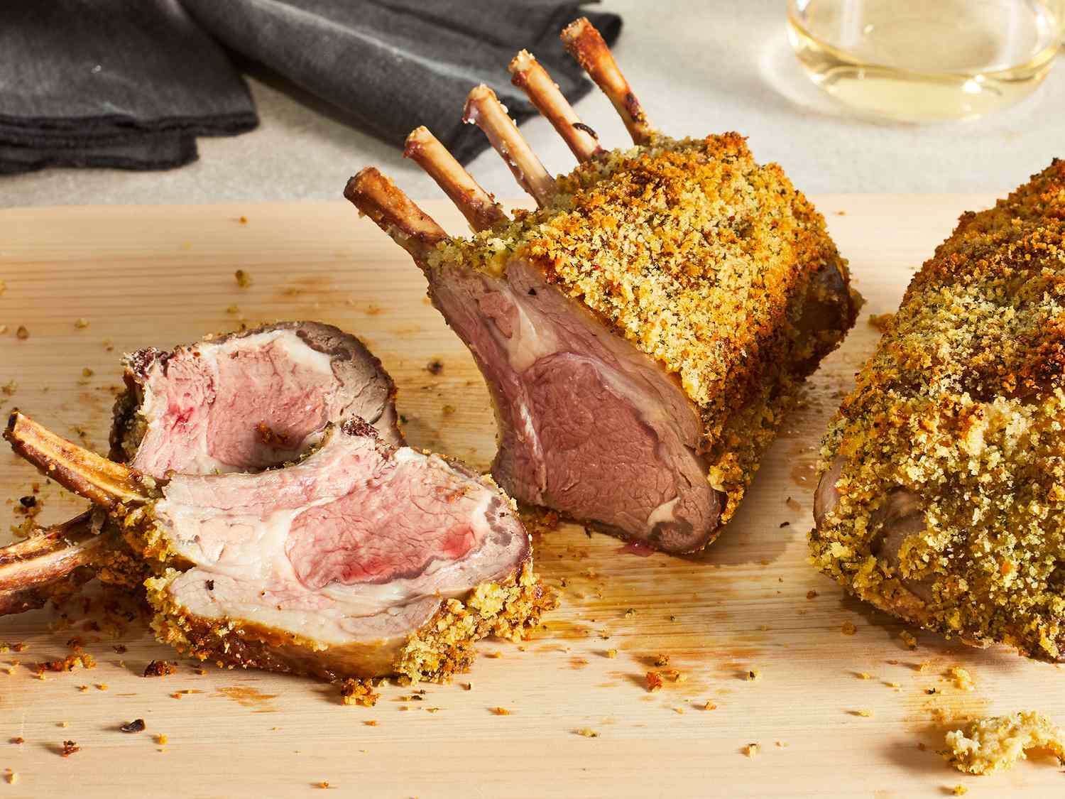 Herb crusted rack of lamb sliced and sitting on a cutting board. 